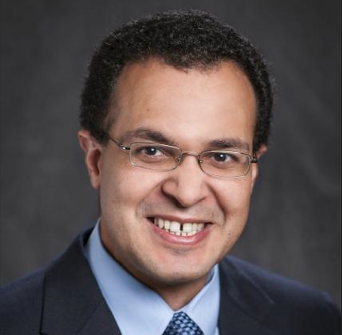 Mostafa Elseifi headshot he is wearing a dark suit in front of a dark grey background.