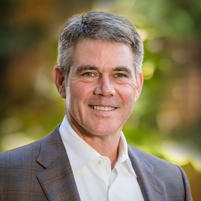 Roy Martin wears a dark suit jacket and smiles for a headshot.